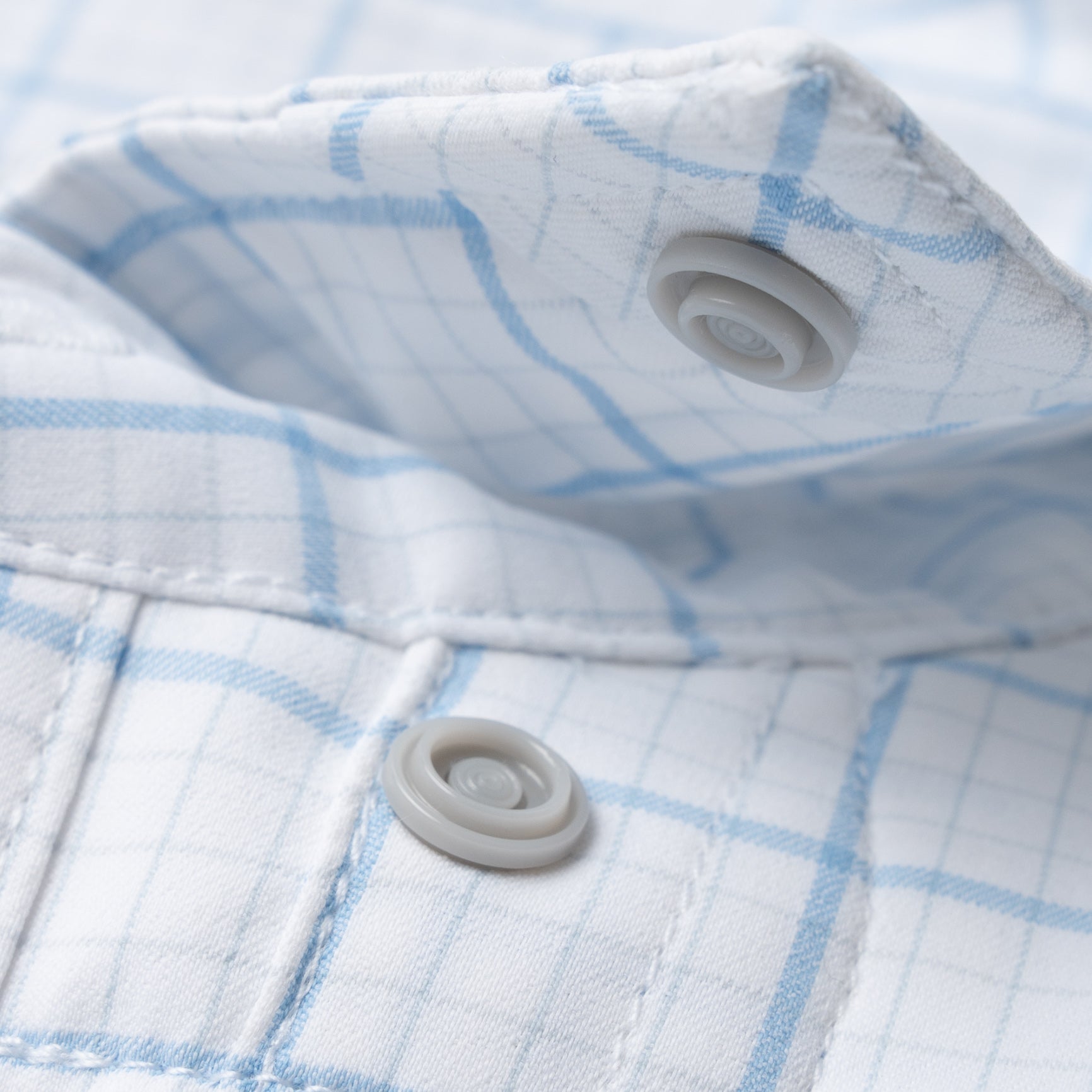 Close up of button snaps on blue plaid shirt