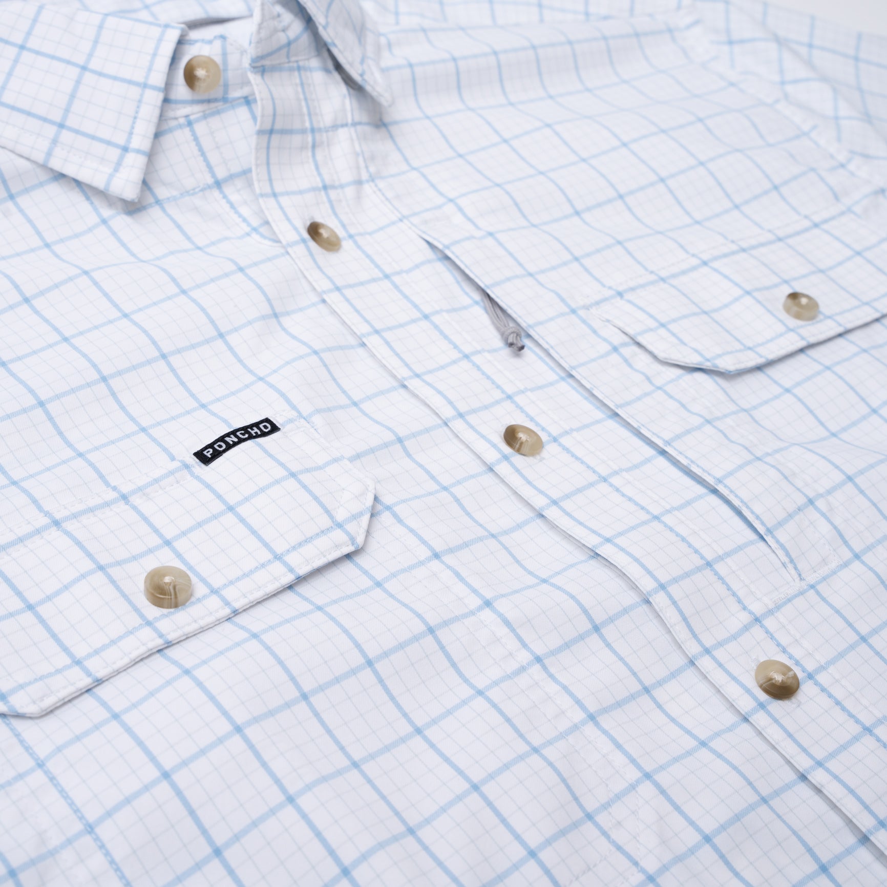 close up photo of button down pockets on white and blue plaid short sleeve