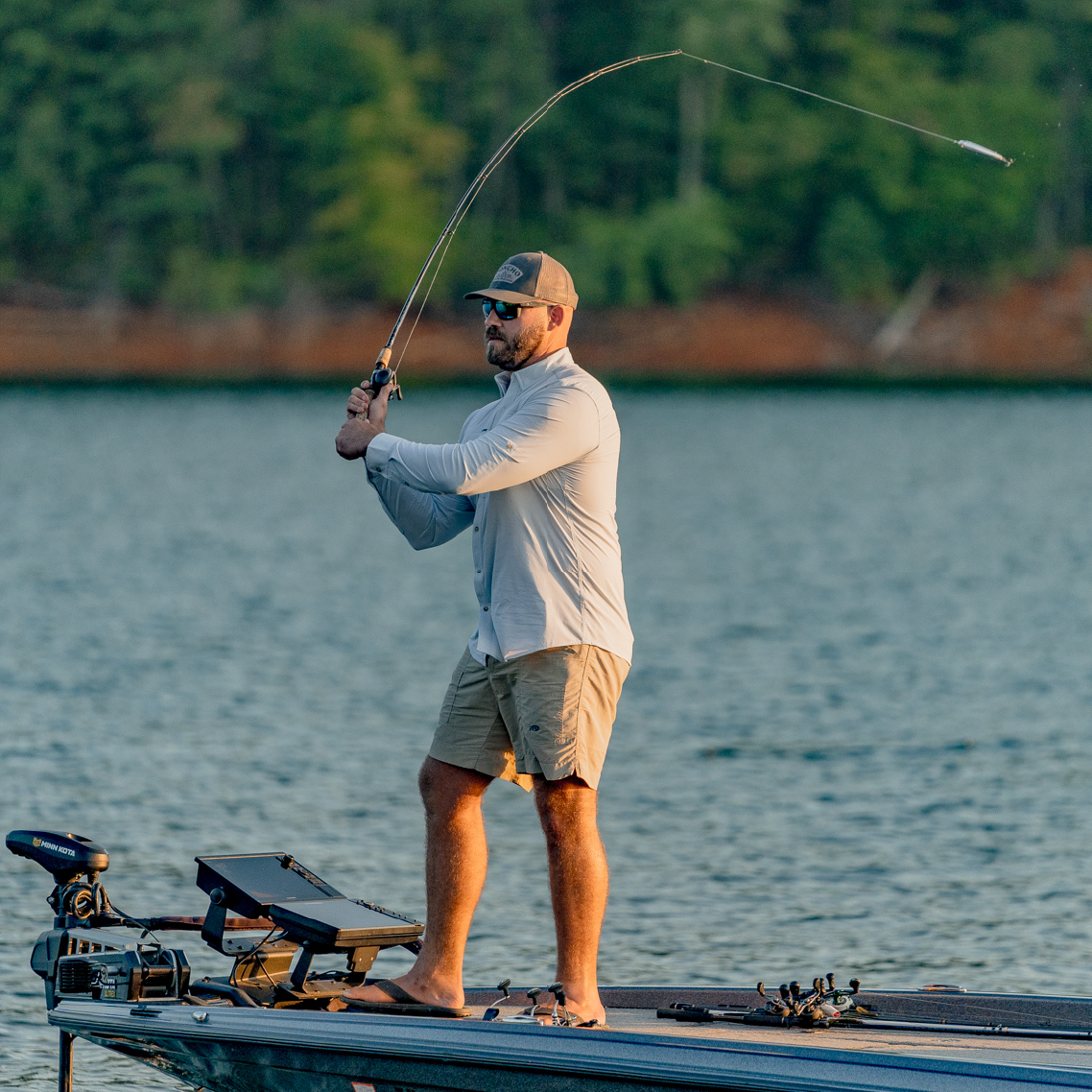 man casting a topwater lure while wearing a green long sleeve button down