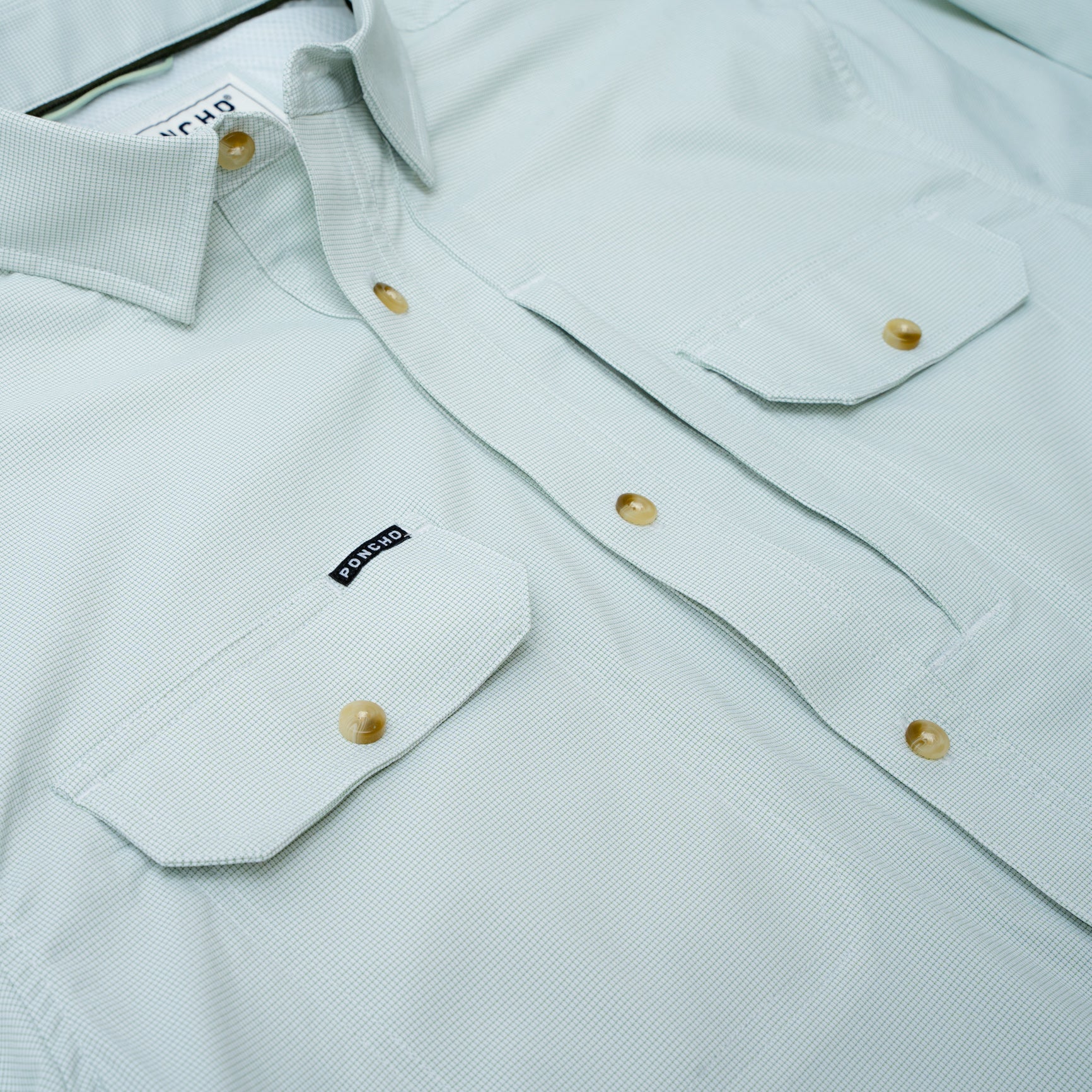 close up photo of chest pockets on micro grid green shirt 