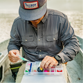 Close up photo of man gearing up for fly fishing in a drift boat