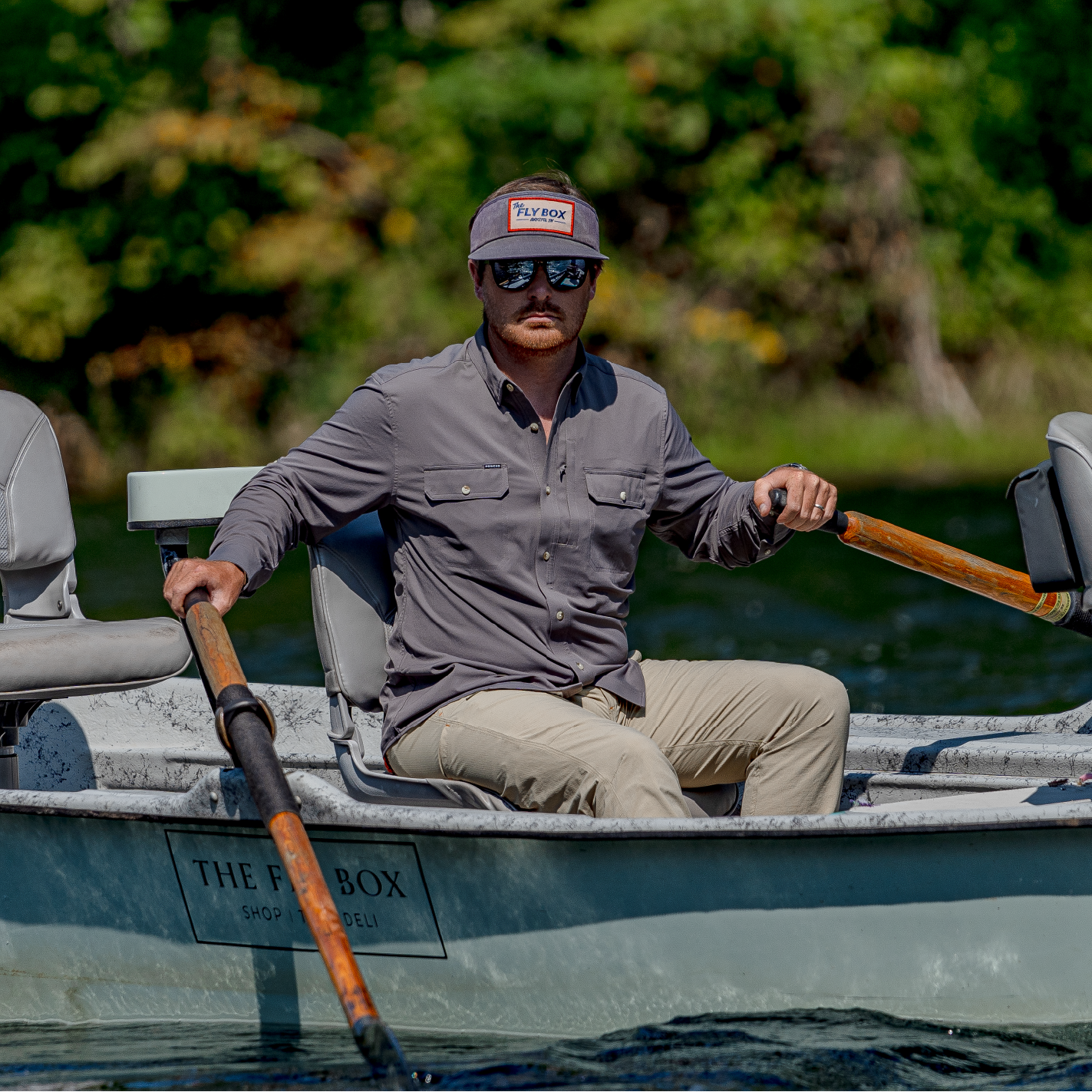 man rowing a drift boat in button down fishing shirt