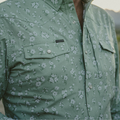 Close up photo of man wearing green shirt in the mountains