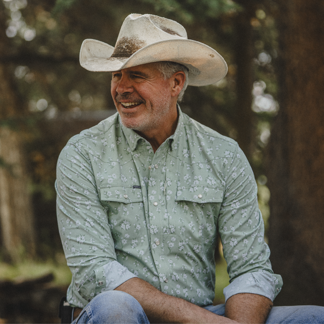 Cowboy wearing green floral long sleeve shirt in the woods