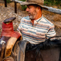 Man putting a saddle on a horse in the mountains