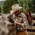 Man reaching into a pack saddle of mule