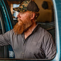 Man getting into truck wearing grey button down shirt