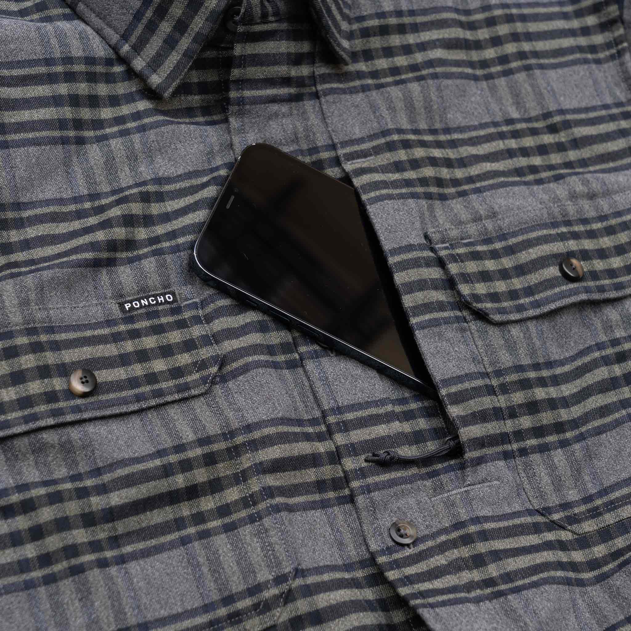 Image of cell phone going into chest pocket on the grey and olive plaid flannel