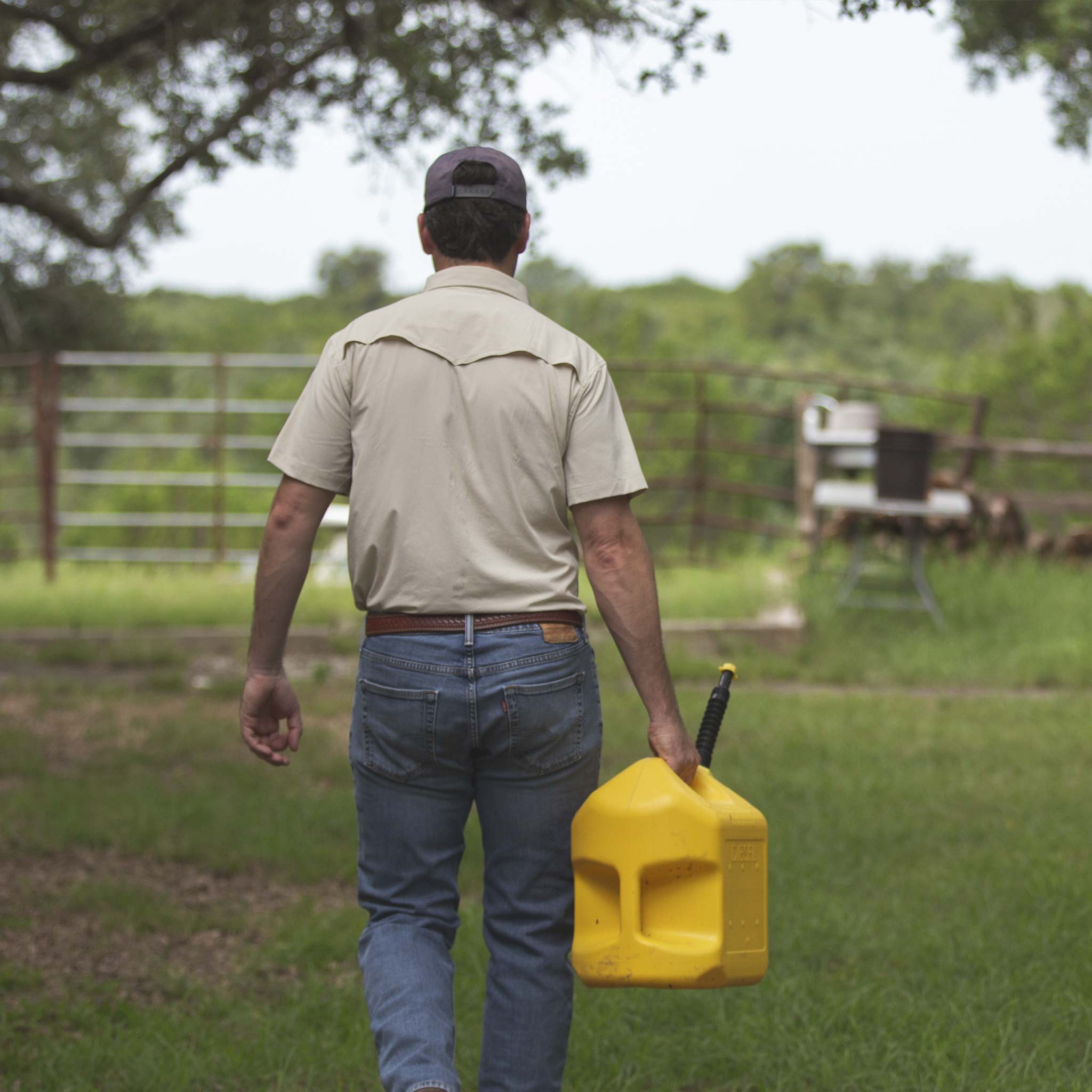 man walks with gasoline while wearing tan short sleeve shirt 